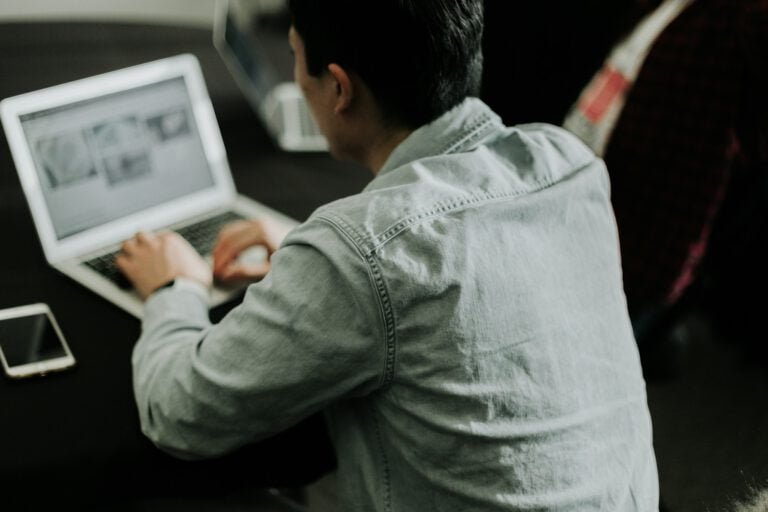 Person working on a laptop with design mockups on the screen, representing the concept of ghost design projects.